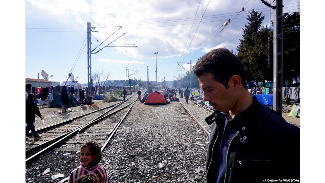 A man walks amid a makeshift encampment, with tents set up between train tracks in the northern Greek border town of Idomeni, March 4, 2016. (J. Dettmer for VOA)