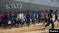 Des migrants marchent sur le quai après avoir débarqué du navire de la marine allemande Frankfurt Am Main dans le port sicilien d'Augusta, Italie, le 12 Avril 2016.