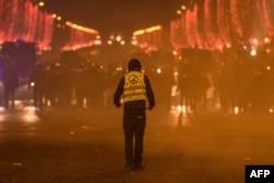 A protester wearing a yellow vest faces riot police during a demonstration of the 'Yellow Vests' (Gilets Jaunes) against rising costs of living on the Champs Elysees avenue in Paris, Dec. 8, 2018.