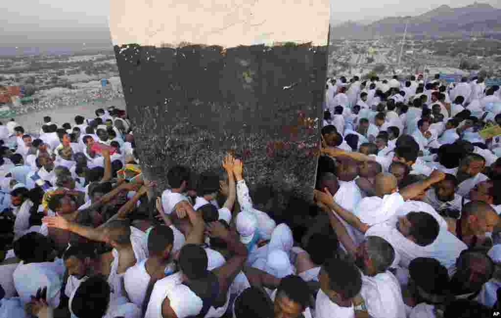 Des pèlerins musulmans prient sur une colline appelée Montagne de la miséricorde, certains touchant un repère à son sommet, dans la Plaine d'Arafat, près de la ville sainte de La Mecque, en Arabie Saoudite, le 14 oct. 2013