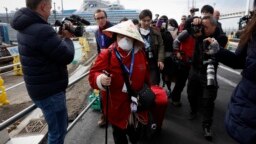 Seorang penumpang (mengenakan masker) dikerumuni oleh awak media saat turun dari kapal pesiar Diamond Princess di pelabuhan Yokohama, Jepang (foto: ilustrasi). 