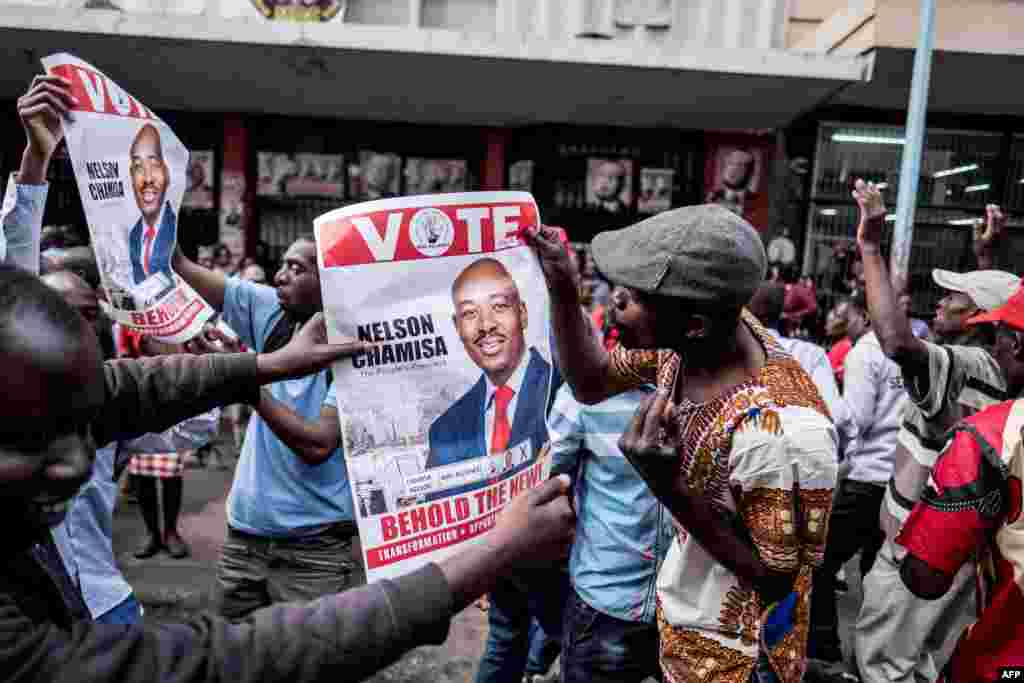 Supporters of Zimbabwe's opposition MDC Alliance party leader Nelson Chamisa hold his campaign posters as they gather outside the MDC Alliance's headquarters in Harare. The government warned election candidates they will face prosecution and jail for prematurely announcing results of landmark polls after the MDC Alliance party said it had won.