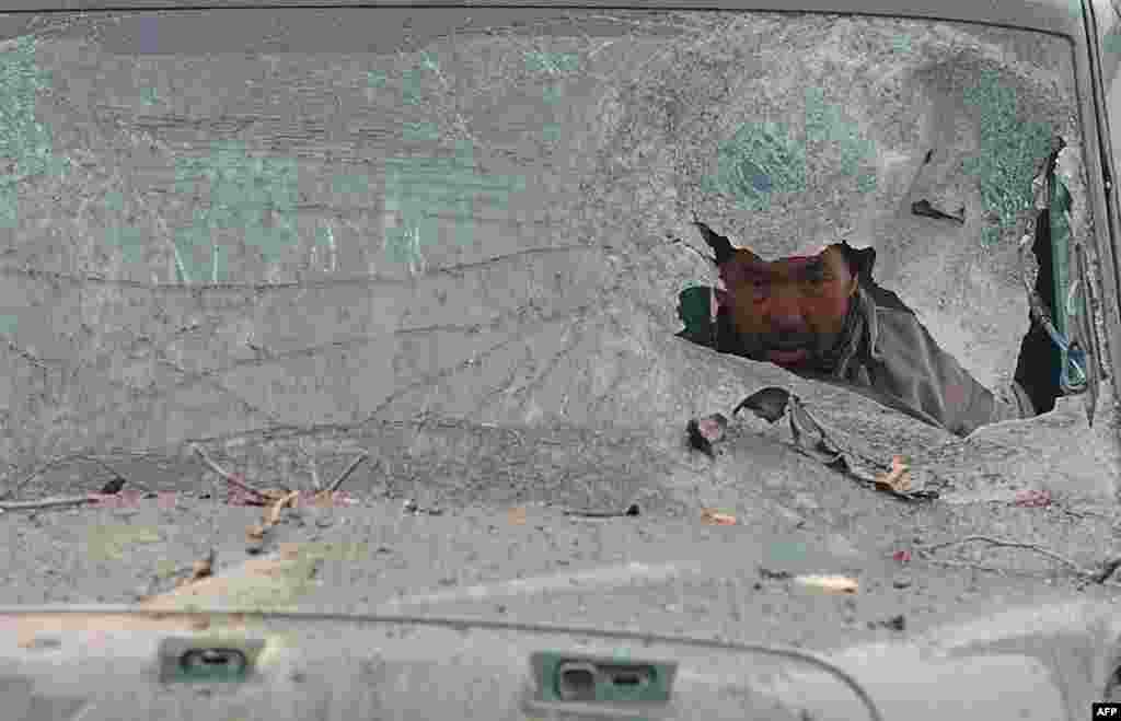 An Afghan truck driver is seen through the broken windshield of his vehicle at the site of a suicide attack near the Afghan intelligence agency headquarters in Kabul. 
