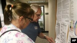 FILE - Dave and Jane Will inspect a sample ballot in Bismarck, N.D., June 5, 2018.