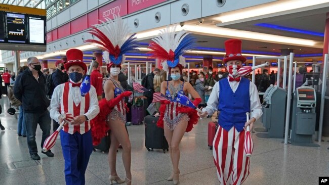 Performers entertain passengers at London Heathrow Airport's T3 as the US reopens its borders to UK visitors in a significant boost to the travel sector, in London, Monday, Nov. 8, 2021. (Steve Parsons/PA via AP)