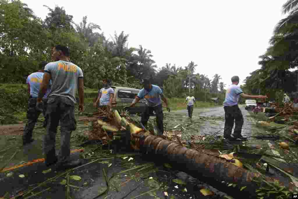 4일 필리핀 콤파스텔라밸리 주에서 고속도로 위로 쓰러진 코코넛 나무를 치우는 경찰들.