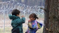 Migrant children eat near the barbed wire fence as migrants gather at the Belarus-Poland border near Grodno, Belarus, Nov. 13, 2021