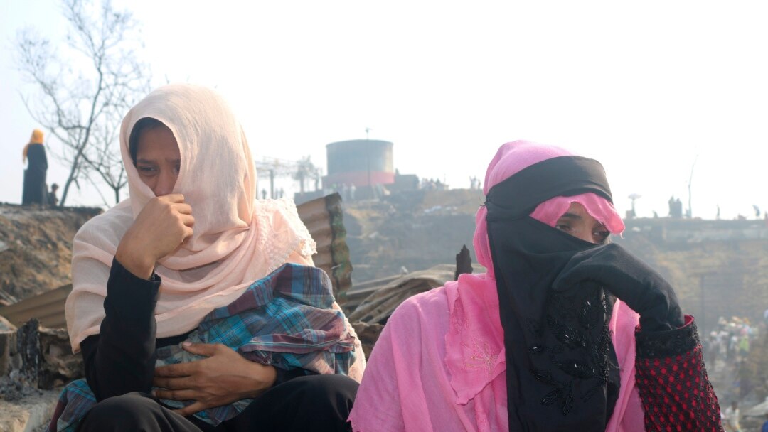 Rohingya refugees cry sitting at the site of Monday's fire at a refugee camp in Balukhali, southern Bangladesh, Tuesday, March 23, 2021. (AP Photo/ Shafiqur Rahman)