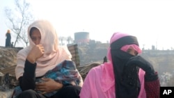Rohingya refugees cry sitting at the site of Monday's fire at a refugee camp in Balukhali, southern Bangladesh, Tuesday, March 23, 2021. (AP Photo/ Shafiqur Rahman)