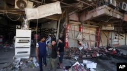Civilians inspect the site of a bomb attack near restaurants and coffee shops filled with customers in central Baghdad's busy commercial Karradah neighborhood, Iraq, May 3, 2015. 