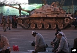 Des manifestants priant sur la place Tahrir du Caire, à proximité d'un char de l'armée