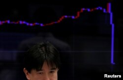 An employee of a foreign exchange trading company works in front of a monitor displaying a graph of the Japanese yen's exchange rate against the U.S. dollar in Tokyo, Japan, Nov. 9, 2016.