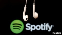 FILE - Earbuds are seen in front of a logo of online music streaming service Spotify in this illustration, Feb. 18, 2014.