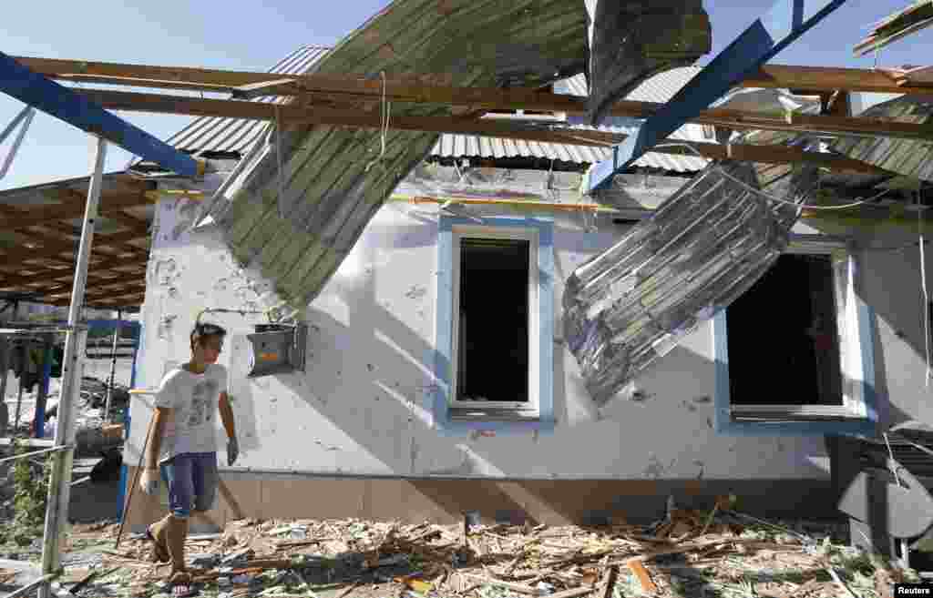 A man walks past a house damaged by recent shelling on the outskirts of the southern coastal town of Mariupol, Ukraine, Sept. 7, 2014. 