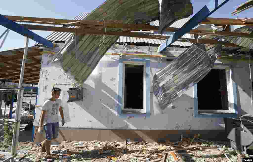 A man walks past a house damaged by recent shelling on the outskirts of the southern coastal town of Mariupol, Ukraine, Sept. 7, 2014.