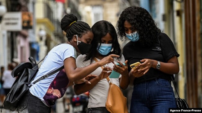 FILE - Women use their phones in a street in Havana, July 14, 2021.