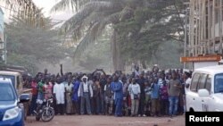 People stand near the Radisson hotel after al-Qaida launched a deadly attack on guests, in Bamako, Mali, Nov. 20, 2015.