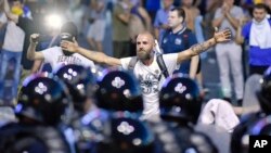 A man stands in front of a riot police line during protests outside the government headquarters, in Bucharest, Romania, Aug. 10, 2018.