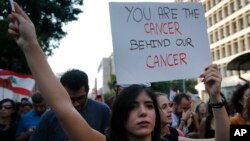 An anti-government protester holds a placard, as she marches during a protest against the central bank and the Lebanese government, in Beirut, Lebanon, Thursday, Oct. 31, 2019.