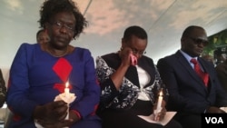 Twenty years after the 1998 U.S. embassy bomb attack in Nairobi, Kenya, emotion overwhelms a survivor (center) at a memorial park. Hundreds gathered there Aug. 7, 2018, to remember. (M. Yusuf/VOA)