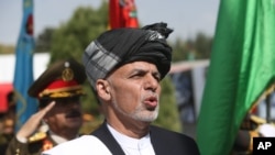 Afghan President Ashraf Ghani sings the national anthem after putting flowers on the "Independence Minaret" monument during Independence Day celebrations at Defense Ministry in Kabul, Aug. 18, 2016. 