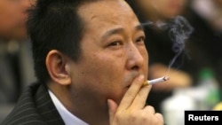 FILE - Liu Han, former chairman of Hanlong Mining, smokes a cigarette during a conference in Mianyang, Sichuan province.