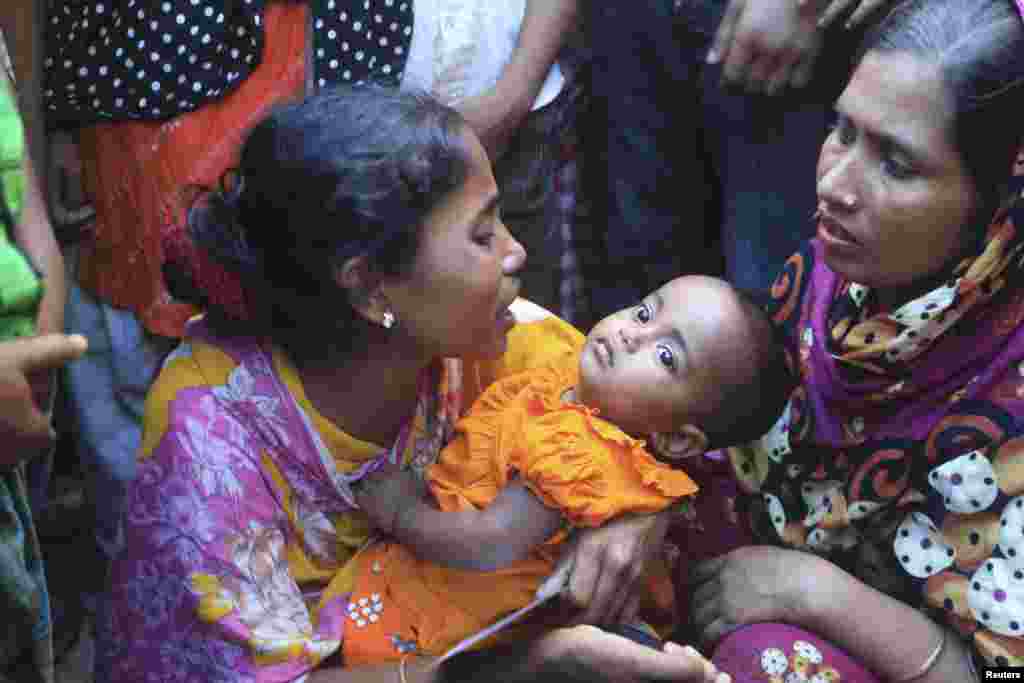 A woman mourns with her child as her relative, a garment worker, is reported missing after a fire inside a garment factory in Gazipur, Bangladesh, Oct. 9, 2013. 