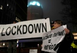 A protester holds a banner during a small anti-COVID restriction demonstration in the Hague, the Netherlands, Dec. 18, 2021.