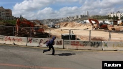 A boy runs past a road under construction in the Arab neighborhood of Beit Safafa in Jerusalem February 28, 2013.