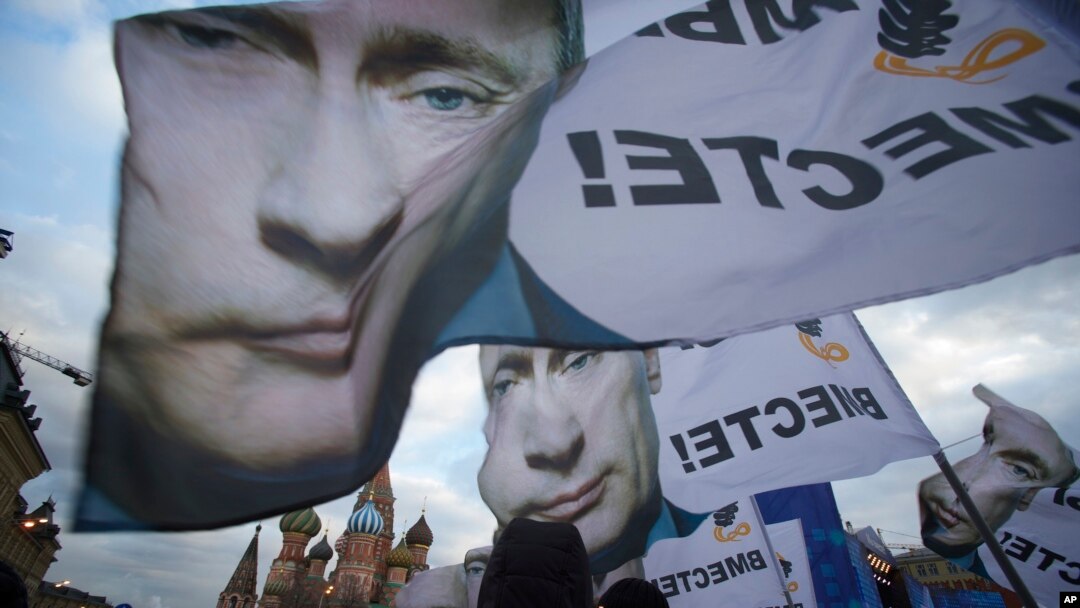 Warga di Moskow memberikan dukungan penggabungan Krimea dengan Rusia, dengan membawa spanduk dan potret Presiden Rusia Vladimir Putin (18/3). (AP/Pavel Golovkin)