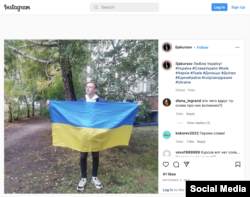 Ilya Kursov holds a Ukrainian flag as part of an anti-war protest. (@iljakursov/Instagram)