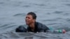 FILE - Achraf, 16, cries as he swims using bottles as floaters, near the fence between the Spanish-Moroccan border, after thousands of migrants swam across the border, in Ceuta, Spain, May 19, 2021. 