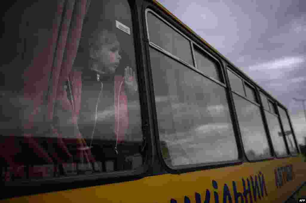 A girl looks out from a bus as families from Russian occupied territories in Ukraine's Zaporizhzhia region arrive in a humanitarian convoy at a registration and processing center for internally displaced people.