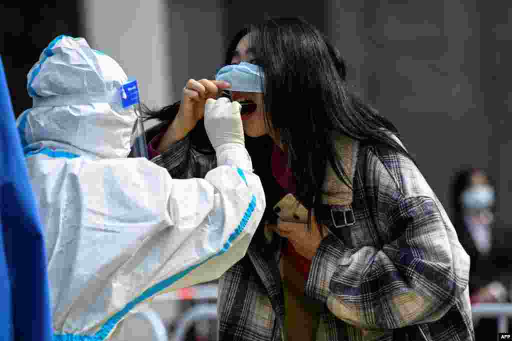 A health worker takes a swab sample from a woman at a Covid-19 coronavirus testing site outside office buildings in Beijing.