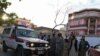 Onlookers stand next to an ambulance carrying victims near the site of a blast in Kabul on April 29, 2022.