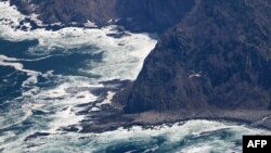 This aerial view from a Jiji Press helicopter shows another helicopter flying near the coast of the northern Japanese island of Hokkaido on April 29, 2022, where a distress signal was made by the sightseeing boat Kazu 1 on April 23. 