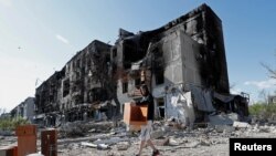 A local resident takes furniture out of an apartment building heavily damaged during Ukraine-Russia conflict in the southern port city of Mariupol, Ukraine, April 28, 2022.