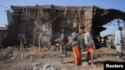 FILE - Residents and militia members stand next to houses destroyed by an airstrike during the fight between the Ethiopian National Defense Forces and the Tigray People's Liberation Front forces in Kasagita town, Afar region, Ethiopia, Feb. 25, 2022.