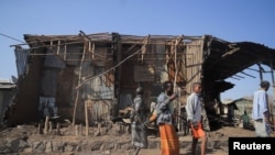 FILE - Residents and militia members stand next to houses destroyed by an airstrike during the fight between the Ethiopian National Defense Forces and the Tigray People's Liberation Front forces in Kasagita town, Afar region, Ethiopia, Feb. 25, 2022.