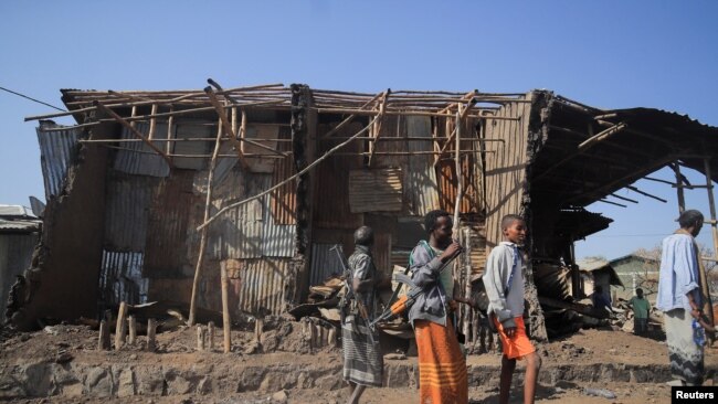FILE - Residents and militia members stand next to houses destroyed by an airstrike during the fight between the Ethiopian National Defense Forces and the Tigray People's Liberation Front forces in Kasagita town, Afar region, Ethiopia, Feb. 25, 2022.