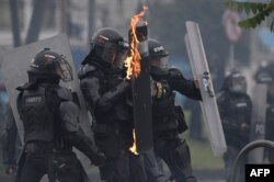 El escudo de un policía antidisturbios se incendia durante una protesta contra el gobierno del presidente colombiano Iván Duque para conmemorar el primer aniversario de un estallido social, frente a la Universidad Nacional en Bogotá, el 28 de abril de 2022.