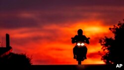 A man rides his bike over a hill on the outskirts of Frankfurt, Germany, as the sun rises.