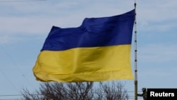 Seorang tentara Ukraina mengibarkan bendera Ukraina di kota Bakhchisaray, Krimea, 10 Maret 2014. (Foto: Reuters)