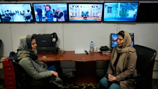 FILE - Afghan journalists Banafsha Binesh, right, speaks with her colleague Wheeda Hassan, at TOLO TV's newsroom in Kabul, Feb. 8, 2022.