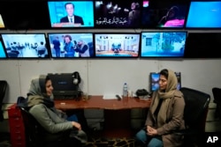 FILE - Afghan journalists Banafsha Binesh, right, speaks with her colleague Wheeda Hassan, at TOLO TV newsroom in Kabul, Feb. 8, 2022. Binesh fear haunts every step when she leaves her home each morning for the newsroom at Afghanistan's largest TV station.