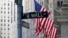 FILE - The Wall St. street sign is framed by the American flags flying outside the New York Stock exchange, Jan. 14, 2022, in the Financial District. The Dow Jones Industrial Average slumped more than 900 points April 28 as another sharp sell-off led by 