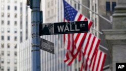 ARCHIVO - El letrero de la calle Wall St. está enmarcado por las banderas estadounidenses que ondean frente a la Bolsa de Valores de Nueva York, el 14 de enero de 2022, en el Distrito Financiero.