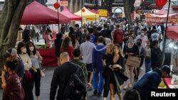 FILE - People walk through a street market in the city center in Sydney, Australia, Nov. 19, 2021. 