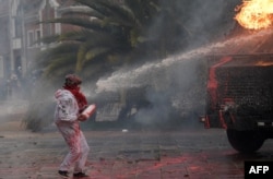 La policía antidisturbios rocía a un manifestante con un cañón de agua durante una protesta contra el gobierno del presidente colombiano Iván Duque para conmemorar el primer aniversario de un estallido social, frente a la Universidad Nacional en Bogotá, el 28 de abril de 2022.