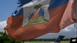 Una bandera haitiana ondea cerca de un avión de carga militar estadounidense estacionado en la pista del aeropuerto Toussaint Louverture en Puerto Príncipe, Haití, el sábado 11 de mayo de 2024.